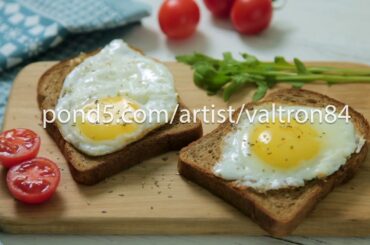 Healthy Breakfast: scrambled eggs on slices of whole-grain bread with arugula and tomatoes on a
