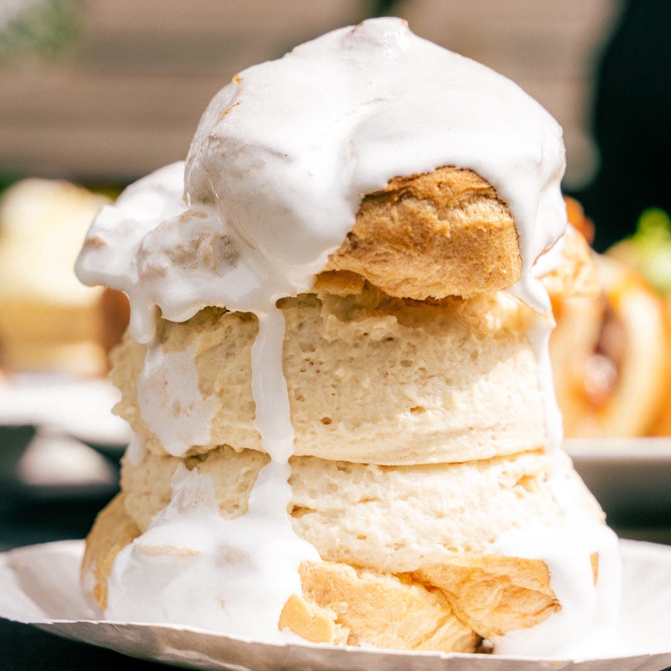 A stack of fluffy biscuits topped with white icing, overflowing and presented on a plate. A stack of fluffy biscuits topped with white icing, overflowing and presented on a plate.