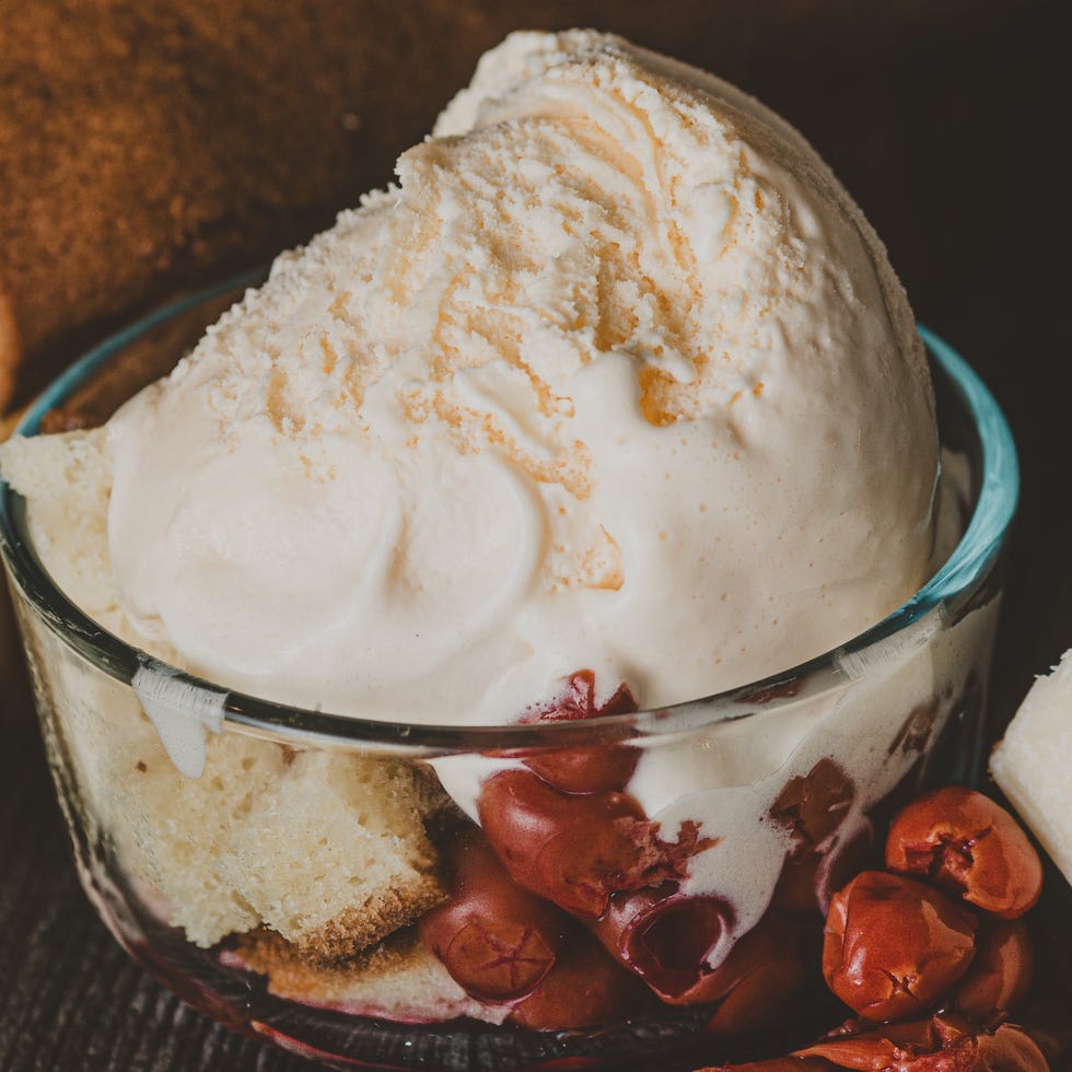 Dessert featuring vanilla ice cream, cherries, and soft cake in a glass bowl. Dessert featuring vanilla ice cream, cherries, and soft cake in a glass bowl.