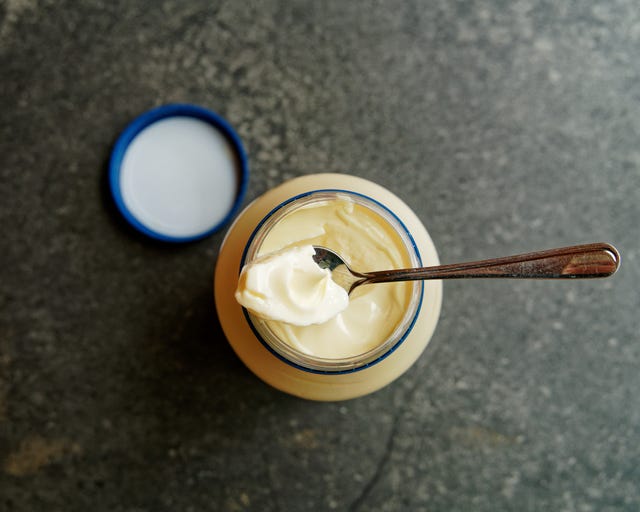 The nipple on the top of a newly opened mayonnaise jar being spooned out. the best bit, the nipple on the top of the mayonnaise in a newly opened jar being spooned out to taste