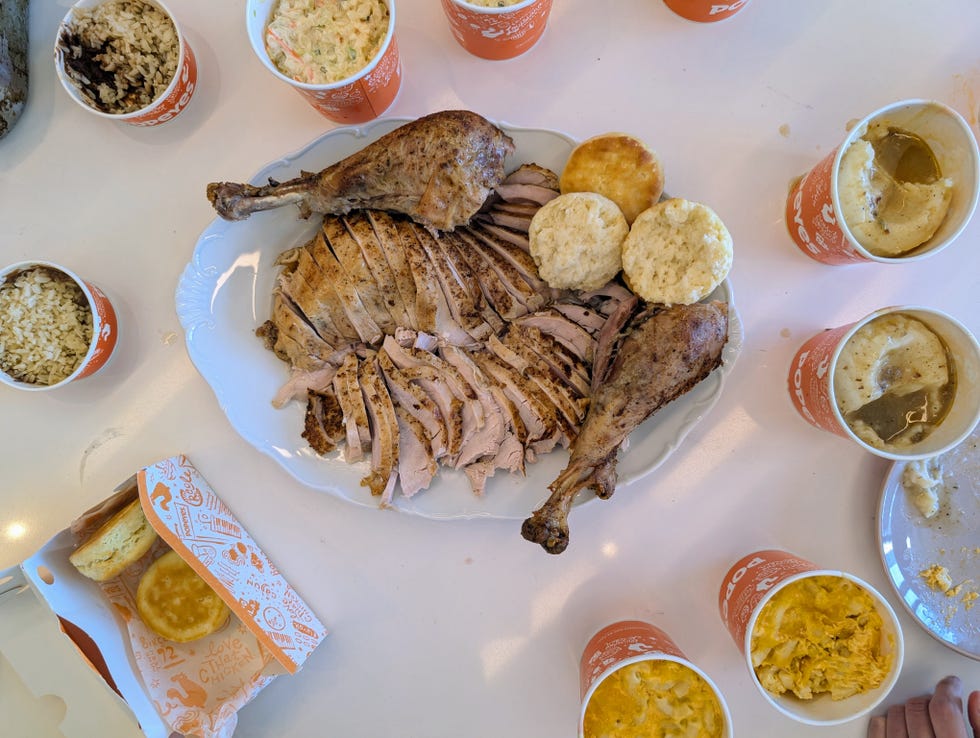 Sliced roasted chicken with biscuits and side dishes of rice, coleslaw, and mashed potatoes on a table. Sliced roasted chicken with biscuits and side dishes of rice, coleslaw, and mashed potatoes on a table.